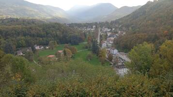 Una valle con un paese incastonato tra le colline, circondato da fitti boschi e vegetazione.