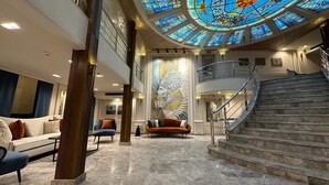 A grand lobby with a high ceiling, a large stained glass window, a staircase, and a seating area with sofas. - Nile Cruise Luxor&Aswon IncludingTours (Luxor)