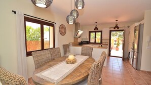 Un comedor con mesa de madera, sillas de mimbre e iluminación colgante.