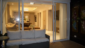 A modern living room with a sofa, a dining area, and a kitchen visible through glass doors. - A Luxe family stay that is 5 minutes from the beach and a step away to the pool. (Punta Cana)