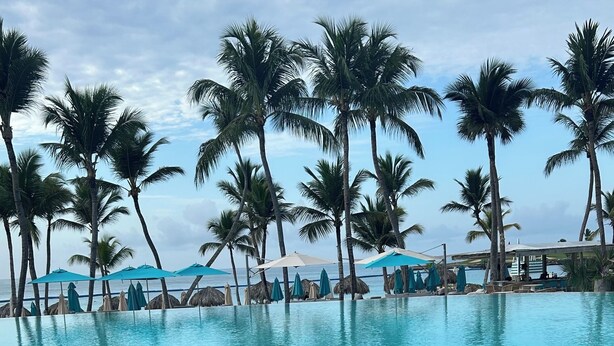 A poolside area with palm trees, lounge chairs, and umbrellas. - A Luxe family stay that is 5 minutes from the beach and a step away to the pool. (Punta Cana)