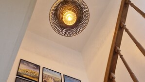En trappa med ett träräcke som leder upp till en liten plattform. Längre ner på väggen hänger en rad inramade affischer som föreställer olika vackra platser.