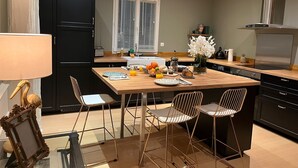 Ett modernt kök med en central köksö, svarta skåp och vitvaror i rostfritt stål.