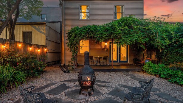 A patio with a stone fire pit, outdoor furniture, and a house with a covered porch.