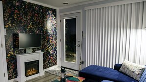 A modern living room with a fireplace, a television, a sofa, and a patterned wall.