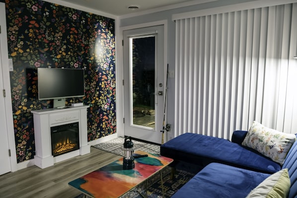 A modern living room with a fireplace, a television, a sofa, and a patterned wall.
