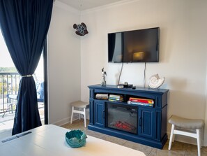 Ein Wohnzimmer mit Fernseher, Kamin und Blick ins Freie.