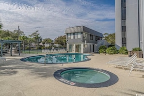 Un área de piscina con dos piscinas, sillas de descanso y un edificio de diseño moderno.