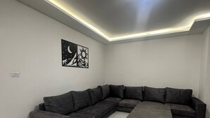A modern living room with a sectional sofa, a coffee table, and a wall art piece depicting a moon and sun.