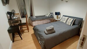 Quarto com cama, escrivaninha, cadeira e janela com persianas.