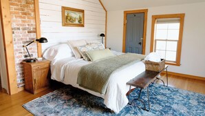 A bedroom with a wooden bed, a nightstand, a lamp, a window, and a door. - Downtown Historic Home / Full Kitchen / W/D / Coffee, Tea, Cold Drinks, Snacks (Moscow)