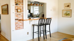 A kitchen with a brick accent wall, a wooden countertop, and two black bar stools. - Downtown Historic Home / Full Kitchen / W/D / Coffee, Tea, Cold Drinks, Snacks (Moscow)