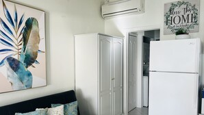 A modern kitchen with white cabinetry, a white refrigerator, and a wall-mounted air conditioner. - Nice and cozy ocean front studio with private terrace. Short walk to beaches. (Beacon Hill)