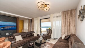 A modern living room with a sofa set, a coffee table, and a TV mounted on a marble wall.