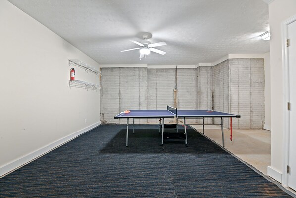 A room with two ping pong tables, a ceiling fan, and a fire extinguisher on the wall. - Tiger's Den on Dean In Auburn, 3BR/2.5BA 3 Miles from Jordan-Hare! (Auburn)