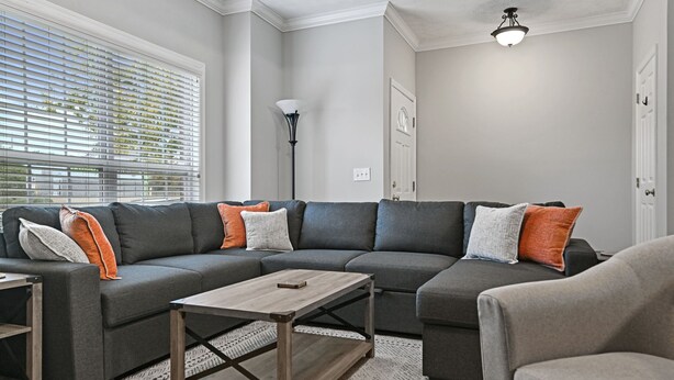 A modern living room with a sectional sofa, a coffee table, and a floor lamp. - Tiger's Den on Dean In Auburn, 3BR/2.5BA 3 Miles from Jordan-Hare! (Auburn)