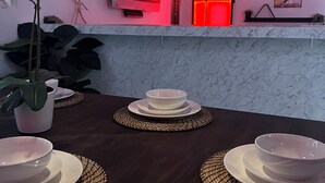 A dining table set with white plates and bowls, a potted plant, and a TV mounted on the wall. - Luxury Full House in Dorado, Puerto Rico (Dorado)