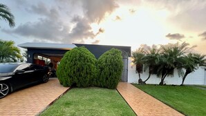 A modern house with a paved driveway, a black car parked on the left, and a well-maintained lawn. - Luxury Full House in Dorado, Puerto Rico (Dorado)