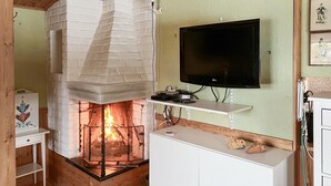 A cozy room with a fireplace, a flat-screen TV mounted on the wall, and a wooden cabinet. - Pet friendly home in Tällberg (Tällberg)