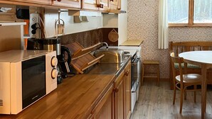 A modern kitchen with wooden cabinets, a built-in oven, and a dining area with a round table and chairs. - Pet friendly home in Tällberg (Tällberg)
