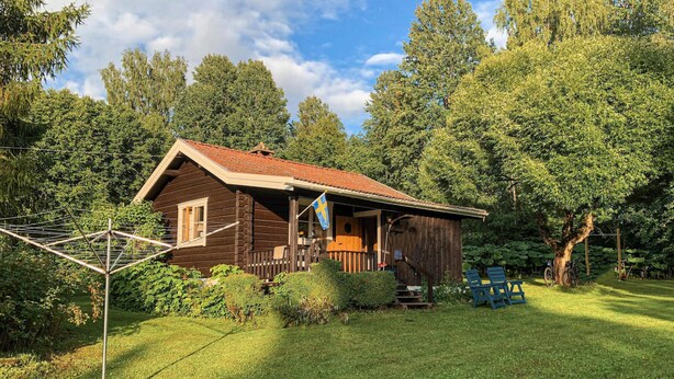 A wooden cabin with a red roof, surrounded by lush greenery and trees. - Pet friendly home in Tällberg (Tällberg)