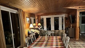 L’intérieur d’un chalet accueillant, avec une table à manger, des chaises, un canapé et un téléviseur.