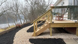Une terrasse en bois avec un escalier en colimaçon menant à un espace abrité où se trouve un fauteuil à bascule.