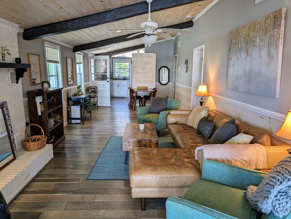 A spacious living room with a large sectional sofa, a dining area, and a kitchen in the background.