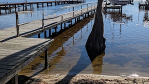 Un muelle de madera que se adentra en aguas tranquilas, con una estructura cubierta al final y un barco atracado cerca.