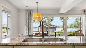 A kitchen with a large window, a sink, and a hanging light fixture. - Escape to Hutchins Lake (Fennville)