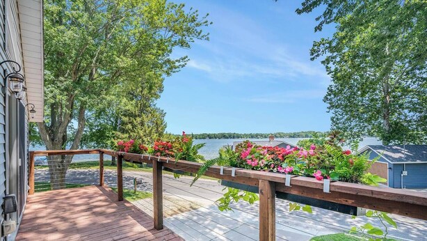 A wooden deck with a railing, overlooking a lake with trees and a clear sky. - Escape to Hutchins Lake (Fennville)