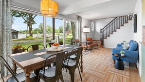 A spacious living area with a dining table, chairs, a sofa, and a staircase. - Escape to Hutchins Lake (Fennville)