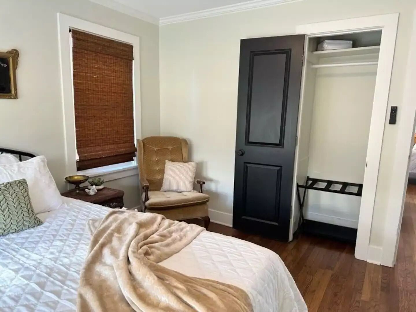Une chambre à coucher avec un lit, une chaise, une armoire et une fenêtre avec des stores.