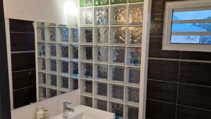 Une salle de bain moderne dotée d’un meuble-lavabo à deux vasques, d’un grand miroir et d’un meuble de rangement intégré avec des portes en verre.