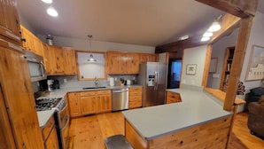 A kitchen with wooden cabinets, a stainless steel refrigerator, and a built-in island.