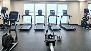 Et fitnessrum med løbebånd, crosstrainere og en romaskine.