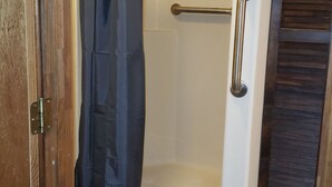 A shower area with a grab bar, a shower curtain, and a wooden door frame.