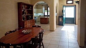 Un comedor con una mesa y sillas de madera, una estantería empotrada y un arco que da a una cocina.