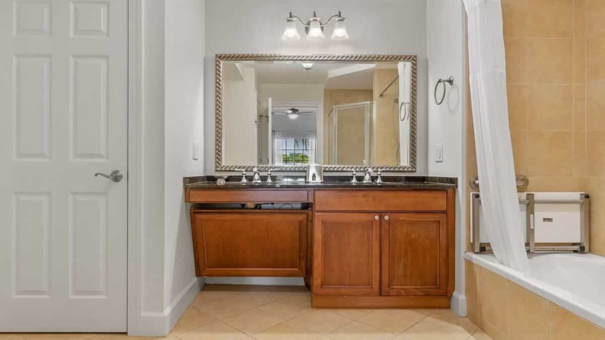 A bathroom with a wooden vanity, a large mirror, a shower curtain, and a bathtub.