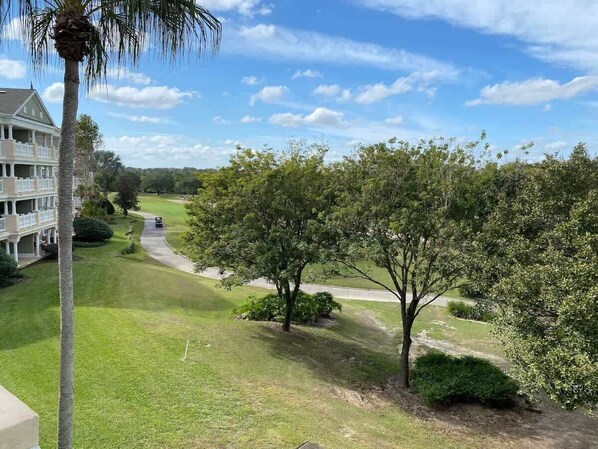 A residential area with a pathway, trees, and a building with balconies.