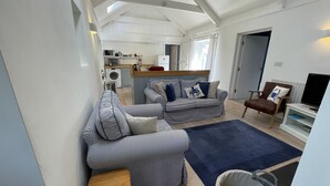 A compact living space with a kitchenette, a sofa, a chair, and a television. - Crugsillick Studio -  a barn conversion that sleeps 4 guests  in 2 bedrooms (Ruan high Lanes)