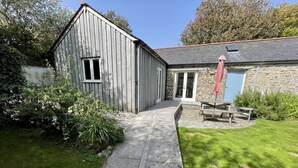 A wooden building with a stone extension, a paved pathway, and a grassy area with a picnic table. - Crugsillick Studio -  a barn conversion that sleeps 4 guests  in 2 bedrooms (Ruan high Lanes)