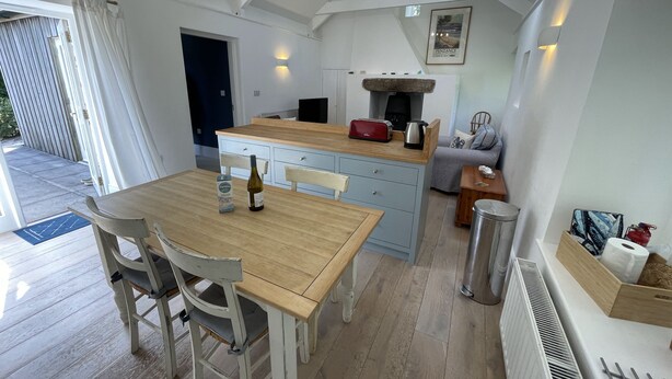 A cozy kitchen with a wooden table, a bottle, and a box of pasta. - Crugsillick Studio -  a barn conversion that sleeps 4 guests  in 2 bedrooms (Ruan high Lanes)