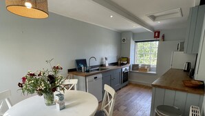 Una cocina moderna con armarios grises, una mesa de comedor blanca y un jarrón con flores.