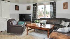 Un salon comprenant un canapé, un fauteuil, une table basse en bois et un téléviseur.