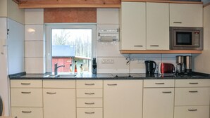 Une cuisine avec des armoires blanches, un four à micro-ondes en acier inoxydable, une machine à café et un grille-pain.