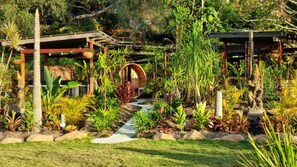 A garden with a wooden pergola, a circular wooden structure, and a statue. - Healing Garden Cabins - Villa Ubud (Tallebudgera Valley)