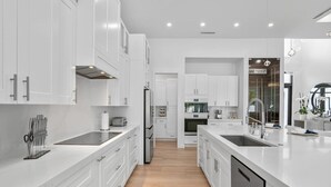A modern kitchen with white cabinetry, stainless steel appliances, and a central island. - Blue Diamond Beach Home (Bonita Springs)