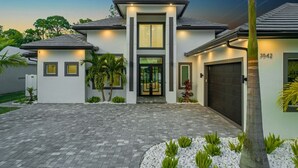 A modern two-story house with a central entrance, a garage, and a well-maintained driveway. - Blue Diamond Beach Home (Bonita Springs)