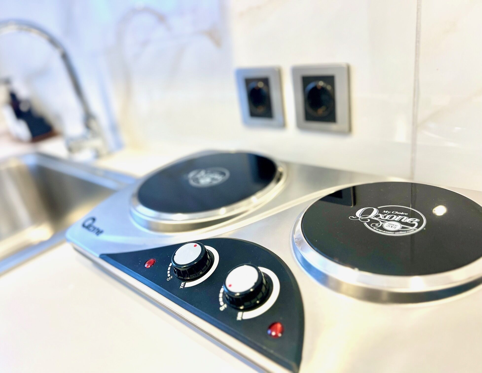 A kitchen with two induction cooktops, a sink, and a faucet.
